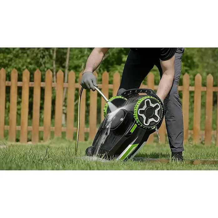 Greenworks Mähroboter AI Mowbot 10 GW KI RTK+VISION - 1.000 m², Schnittbreite: 20 cm, Satellitengestützte Navigation, RTK - Eine Person reinigt einen schwarz-grünen Rasenmäher mit einem Schlauch auf Rasen.