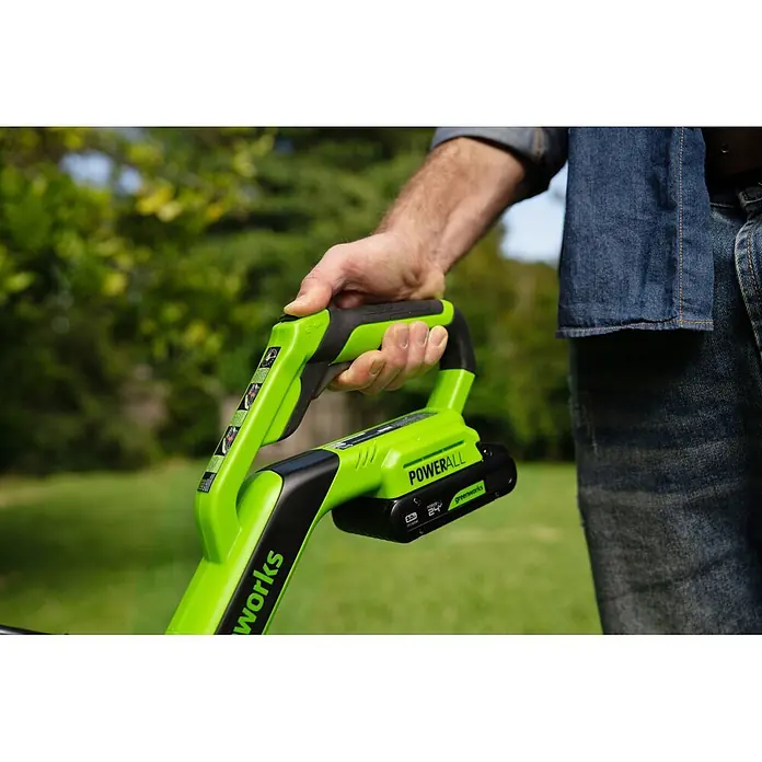 Greenworks Akku-Rasentrimmer 24V BL 30 cm - 24 V, 2 Ah, Li-Ionen, 1 Akku, Schnittbreite Messer: 30 cm, Schnittbreite Faden: 30 cm - Eine Person hält ein leuchtend grünes Greenworks POWERALL 24V Akku-Werkzeug mit schwarzen Akzenten, einsatzbereit.