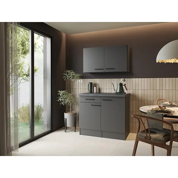 Respekta Buffetschrank - Breite: 100 cm, Grau Matt, Mit Oberschrank - Dunkelgraue Küchenunterschrank- und Wandschrank-Kombination in einer modernen Küche neben einem Fenster, mit Pflanzen und Kaffeezubehör.
