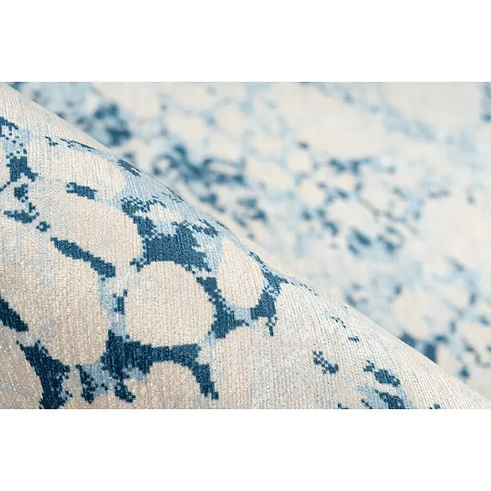 Kayoom Flachgewebeteppich Galaxy - Creme/Blau, 150 x 80 cm, 100 % Polyester - Nahaufnahme eines abstrakten Teppichmusters mit blauen und cremefarbenen Farbtönen, das eine weiche Textur und ein modernes Design zeigt.