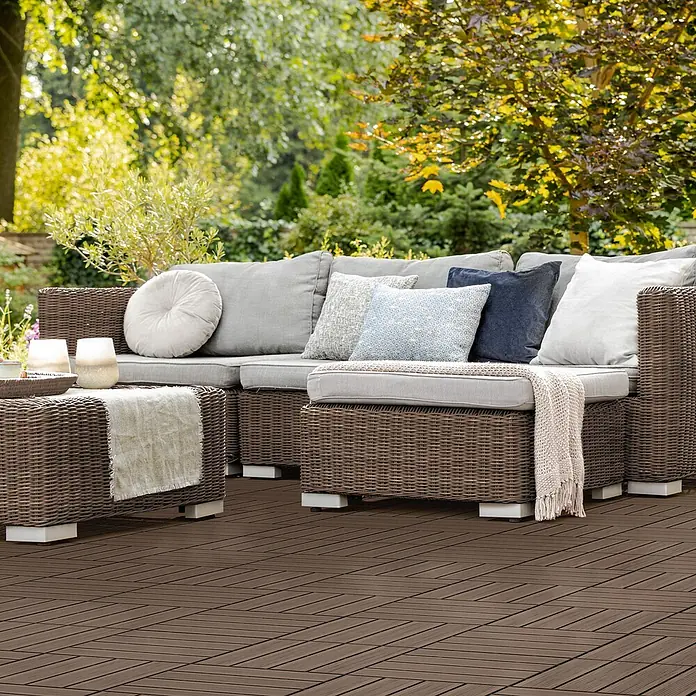 ECD Germany Terrassenfliese Bodenbelag 2m²/22 Stück Dunkelbraun rutschfest Balkonfliesen - 30 cm x 30 cm x 20 mm, Dunkelbraun - Braunes Outdoor-Sofa und Couchtisch im Rattan-Stil mit grauen Kissen und Zierkissen auf einer Terrasse, umgeben von Grün.