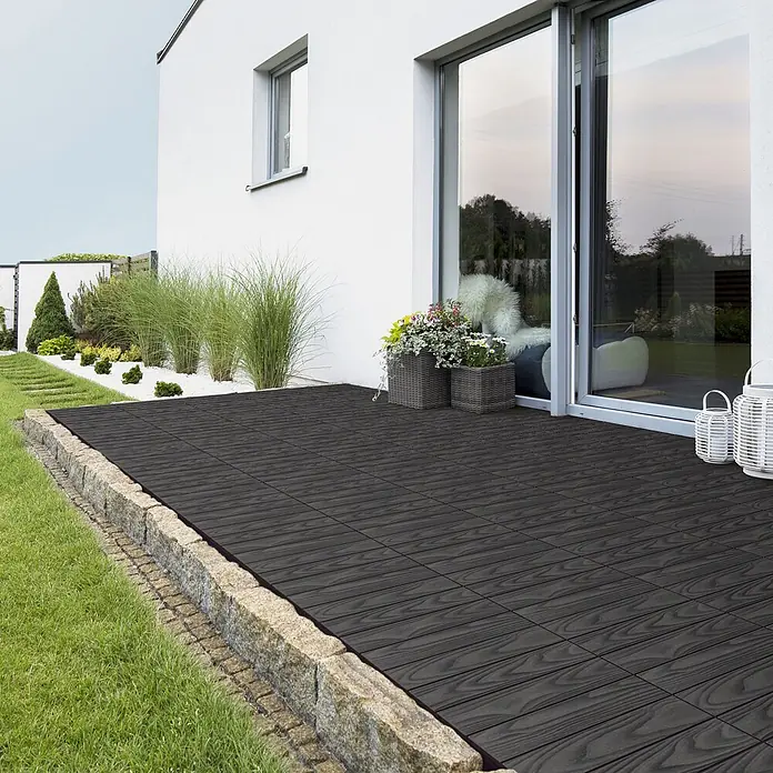 ML-Design Terrassenfliese Bodenbelag 1m²/11 Stück Anthrazit rutschfest Balkonfliesen - 30 cm x 30 cm x 20 mm, Anthrazit - Dunkle Terrassenfliesen in Holzoptik bilden eine Terrasse neben einem modernen Haus und zeigen ihre strukturierte Oberfläche.