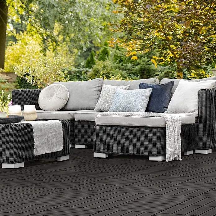 ECD Germany Terrassenfliese Bodenbelag 1m²/11 Stück Anthrazit rutschfest Balkonfliesen - 30 cm x 30 cm x 20 mm, Anthrazit - Dunkelgraue Rattan-Gartenlounge mit hellgrauen Polstern und Kissen auf einer Terrasse im Garten.