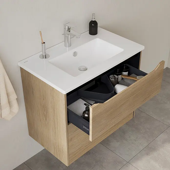 VitrA Integra Square Badmöbel-Set - Gesamtbreite Badmöbel: 80 cm, Eiche Gold - Wandhängender Badezimmerschrank mit heller Holzmaserung, weißem Waschbecken und offener dunkelgrauer Schublade mit Toilettenartikeln.