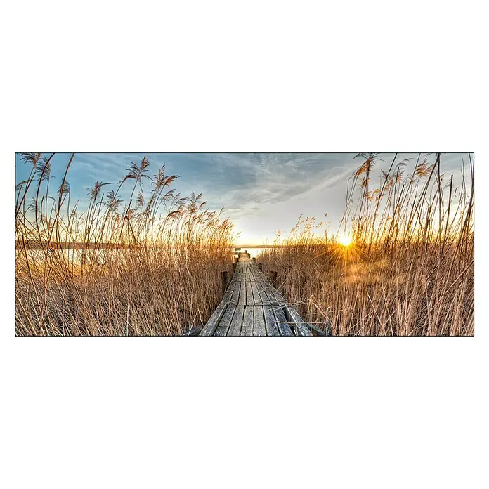 ProArt Glasbild - Way to the Sun, B x H: 125 x 50 cm - Ein Holzsteg führt durch Schilfgras zu einem ruhigen See bei Sonnenuntergang, die warmen Farben des Himmels spiegeln sich im Wasser.