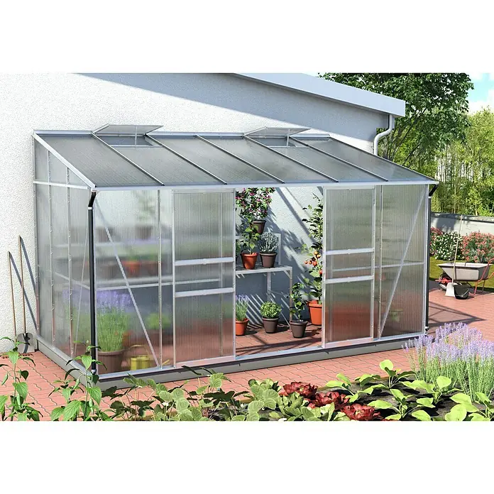 Vitavia Gewächshaus Osiris 7800 - Außenmaß inkl. Dachüberstand (B x T): 368,5 x 201 cm, 6 mm, Aluminium - Nahaufnahme eines Gewächshauses mit Pflanzen und Blumen in Töpfen, das an einem sonnigen Tag an ein Gebäude angebaut ist.