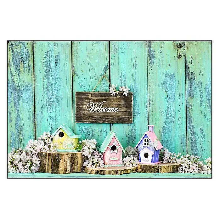 Cuadro Bienvenida - Welcome, An x Al: 90 x 60 cm - La imagen muestra tres casitas de pájaros decorativas en colores pastel sobre rodajas de madera, con un cartel de 'Bienvenido' frente a un panel de madera azul.