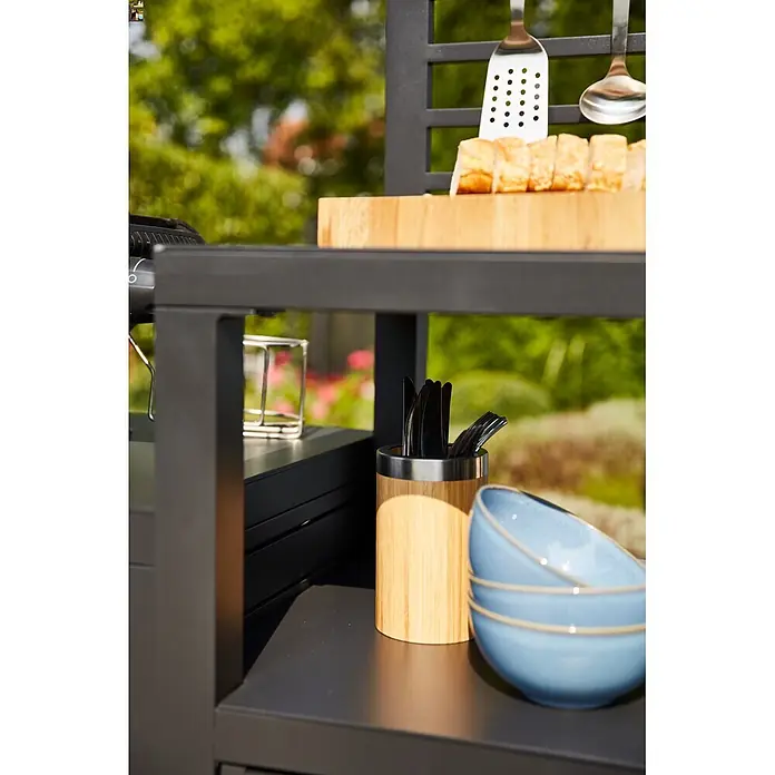 Siena Garden Outdoorküche Texas - 2 -tlg., Anthrazit - Schwarzer Outdoor-Küchenwagen mit Regalen, Schneidebrett, hängenden Werkzeugen, Besteck und blauen Schüsseln im Garten.