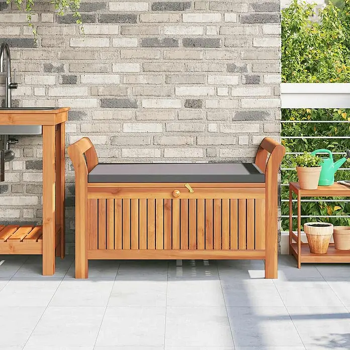 Furnicato Gartenbank Akazien-Massivholz geölt - B x T x H: 50 x 91 x 60 cm, Grau - Outdoor-Sitzbank aus Holz mit dunklem Polster, bietet Sitzgelegenheit und Stauraum auf einer Terrasse.