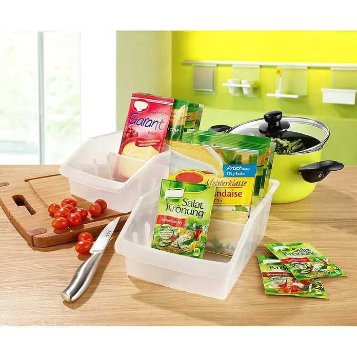Ruco Schrank-Organisator - L x B x H: 24 x 16 x 9 cm, Transparent - Verschiedene Lebensmittelprodukte, darunter Salatkrönung, Grießbrei und Butter, sind in transparenten Behältern und auf einem Tisch arrangiert.