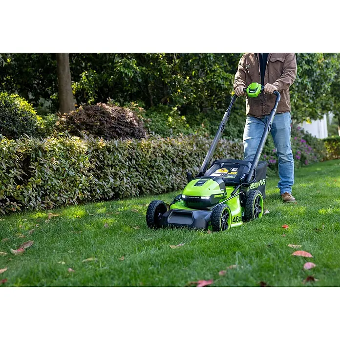 Greenworks Akku-Rasenmäher GW 2X24V BL 46 cm - 24 V, Ohne Akku, Schnittbreite: 46 cm - Eine Person mäht einen Rasen mit einem grün-schwarzen Greenworks Rasenmäher, beschriftet mit "BRUSHLESS" und "46cm".