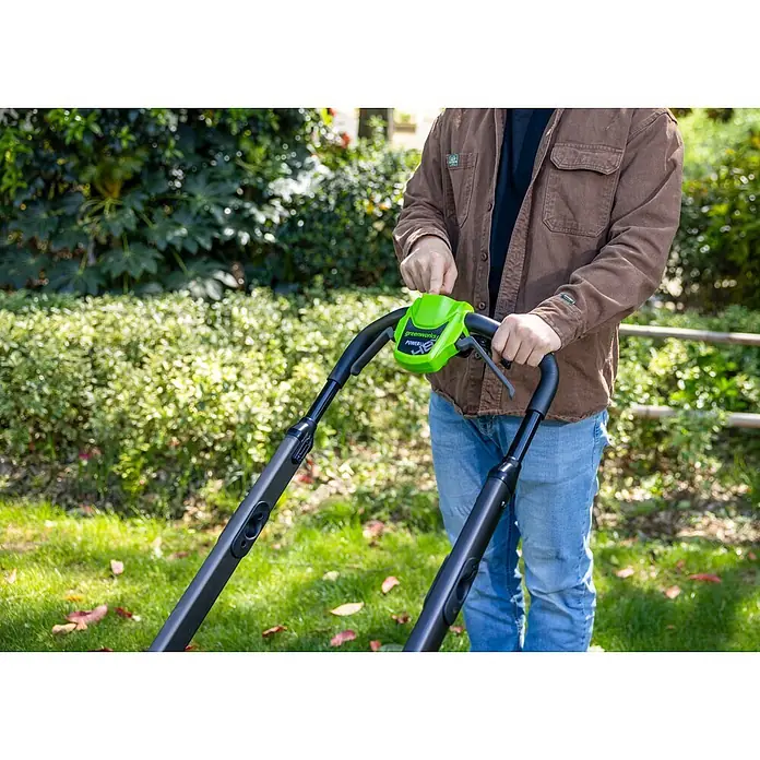 Greenworks Akku-Rasenmäher GW 2X24V BL 46 cm - 24 V, Ohne Akku, Schnittbreite: 46 cm - Person hält einen leuchtend grünen und schwarzen Greenworks Akku-Rasentrimmer, bereit für die Gartenarbeit.