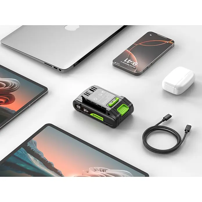Greenworks Akku & Ladegerät 24V 2 AH, VD - Akkuspannung: 24 V, Li-Ionen, 2 Ah - Schwarz-grüner Greenworks 24V POWERALL Akku mit USB-C-Ausgang, umgeben von Laptop, Handy, zwei Tablets, AirPods und USB-C-Kabel.