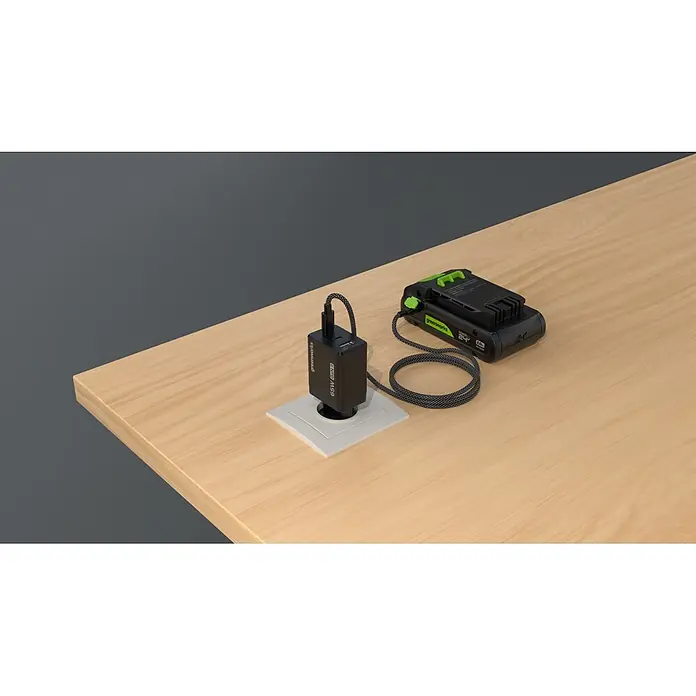 Greenworks Akku & Ladegerät 24V 2 AH, VD - Akkuspannung: 24 V, Li-Ionen, 2 Ah - Greenworks 24V Akku lädt mit schwarzem 65W GaN II USB-Ladegerät und geflochtenem Kabel, angeschlossen an Holztisch.