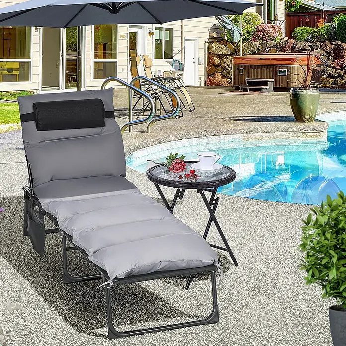 Furnicato Gartenliege Polyestergewebe - B x T: 58 x 189 cm, Hellgrau, Verbundwerkstoff - Grauer gepolsterter Liegestuhl mit schwarzer Kopfstütze und Beistelltisch am Pool, unter einem Sonnenschirm.