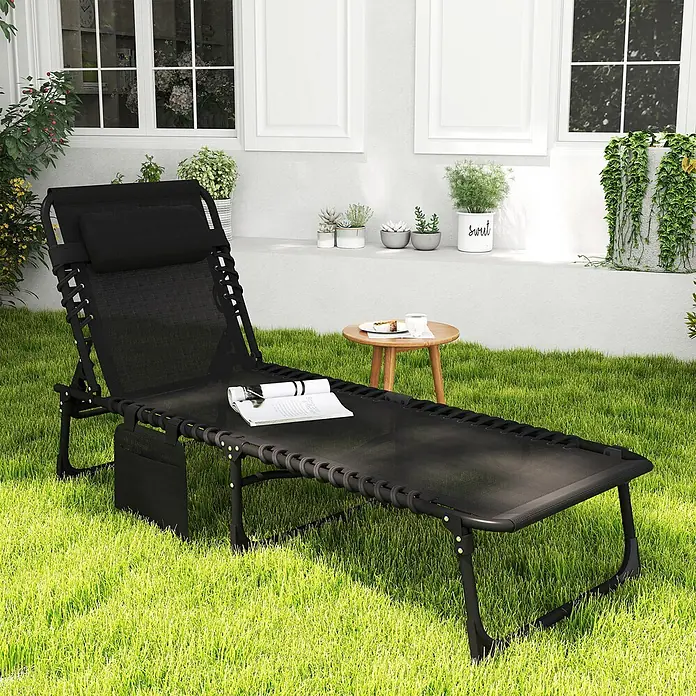 Furnicato Gartenliege - B x T: 58 x 185 cm, Schwarz, Polyester - Schwarze Netz-Chaiselongue mit Kissen in einem Garten, mit Buch und Beistelltisch.