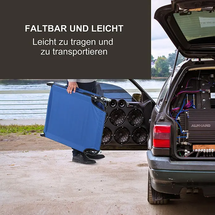 Furnicato Gartenliege - B x T: 56 x 188 cm, Blau, Polyester - Blauer, zusammengeklappter Feldsessel wird von einer Person neben einem Auto getragen, was seine Transportfähigkeit hervorhebt.