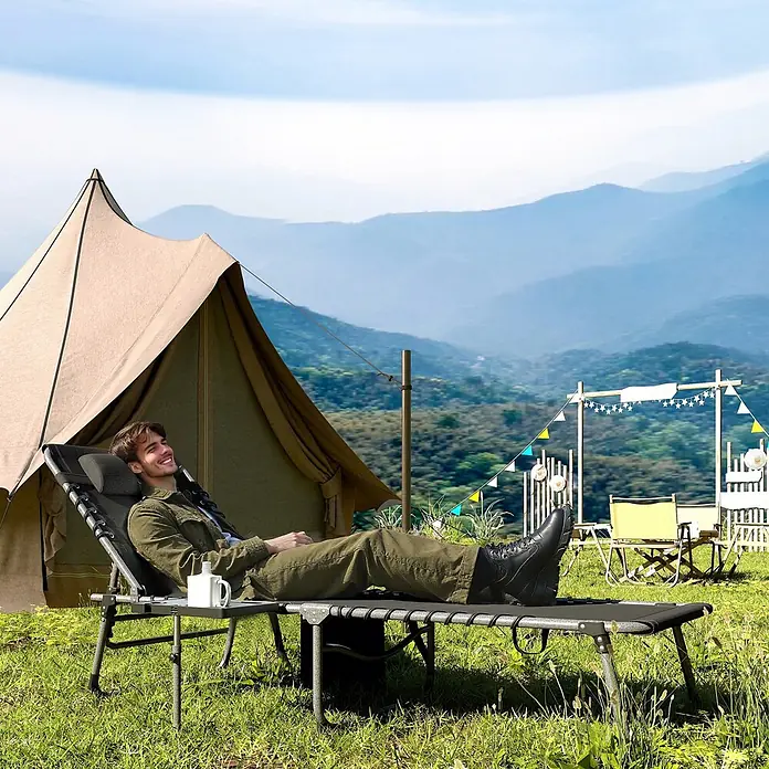 Outsunny Gartenliege - B x T: 60 x 190 cm, Schwarz, Stahl, Rückenlehne verstellbar - Schwarze Campingliege mit Beistelltisch, von einem Mann zum Entspannen im Freien neben einem Zelt genutzt.