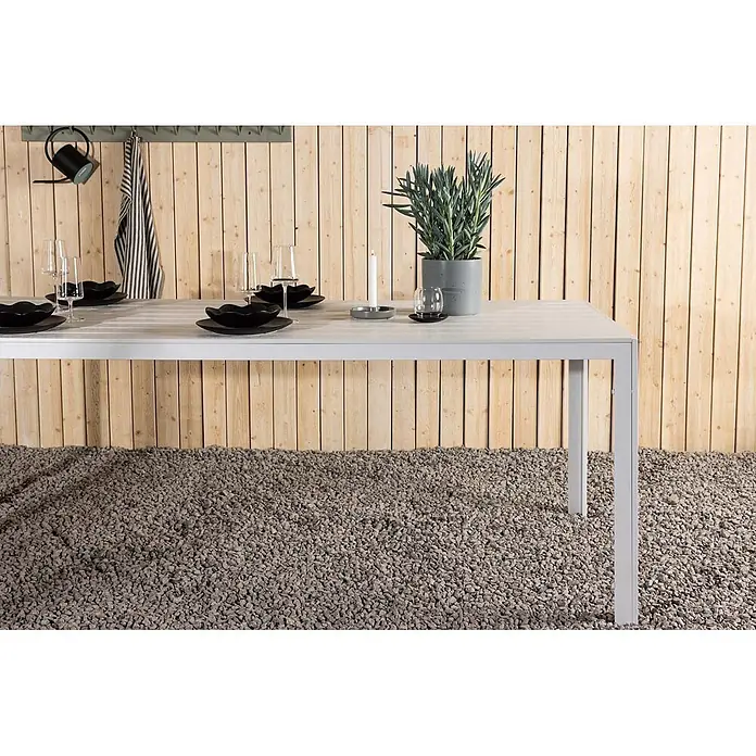 Ebuy24 Gartentisch Break - L x B x H: 205 x 90 x 75 cm, Ø x H: 90 x 75 cm, Aluminium, Weiß - Weißer Lamellen-Esstisch für draußen, gedeckt mit schwarzen Tellern, Gläsern und einer Pflanze.