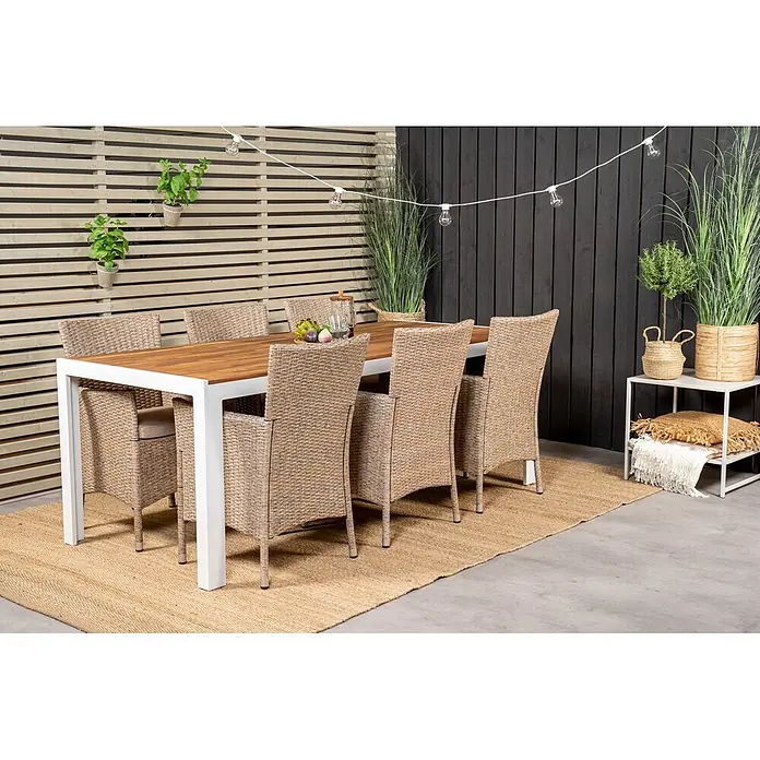 Ebuy24 Gartentisch Bois - L x B x H: 205 x 90 x 76 cm, Ø x H: 90 x 76 cm, Akazie, Aluminium, Sonstige, Weiss - Eine Outdoor-Essgruppe mit Holztisch, weißem Gestell und sechs geflochtenen Stühlen mit beigen Kissen auf einem Teppich.