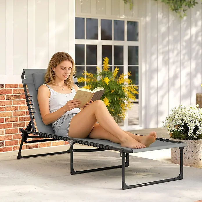 Outsunny Gartenliege - B x T: 58 x 189 cm, Grau, Stahl, Klappbar - Grauer Outdoor-Liegestuhl, von einer Frau zum Entspannen und Lesen auf einer Terrasse genutzt.