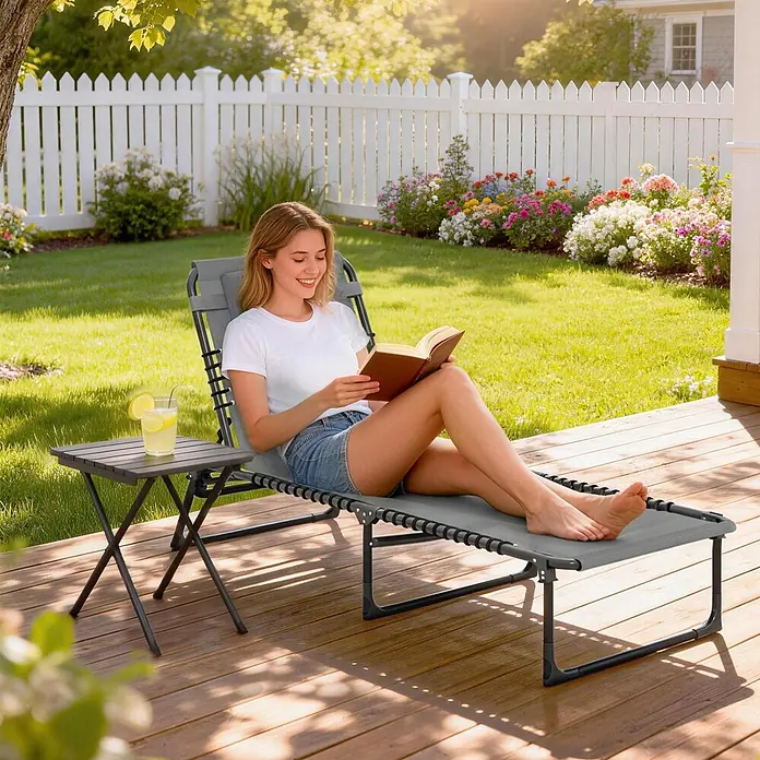 Outsunny Gartenliege - B x T: 58 x 189 cm, Grau, Stahl, Klappbar - Grauer Zero-Gravity-Liegestuhl mit passendem Beistelltisch auf einer Terrasse, von einer Frau zum Entspannen genutzt.
