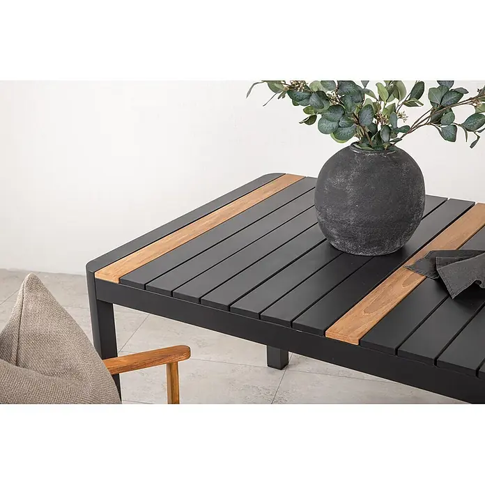 Ebuy24 Gartentisch Togo - L x B x H: 150 x 90 x 75 cm, Ø x H: 90 x 75 cm, Aluminium, Sonstige, Schwarz - Dunkelgrauer Lamellen-Außentisch mit Naturholz-Akzenten, dekoriert mit einer Vase mit Grünpflanzen und einer Serviette.