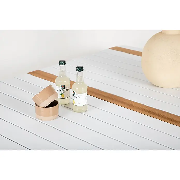 Ebuy24 Gartentisch Togo - L x B x H: 150 x 90 x 75 cm, Ø x H: 90 x 75 cm, Aluminium, Sonstige, Weiß - Weißer Lamellentisch mit Holzdetails, darauf zwei Limonadenflaschen, gestapelte Keramikbecher und eine Keramikvase.