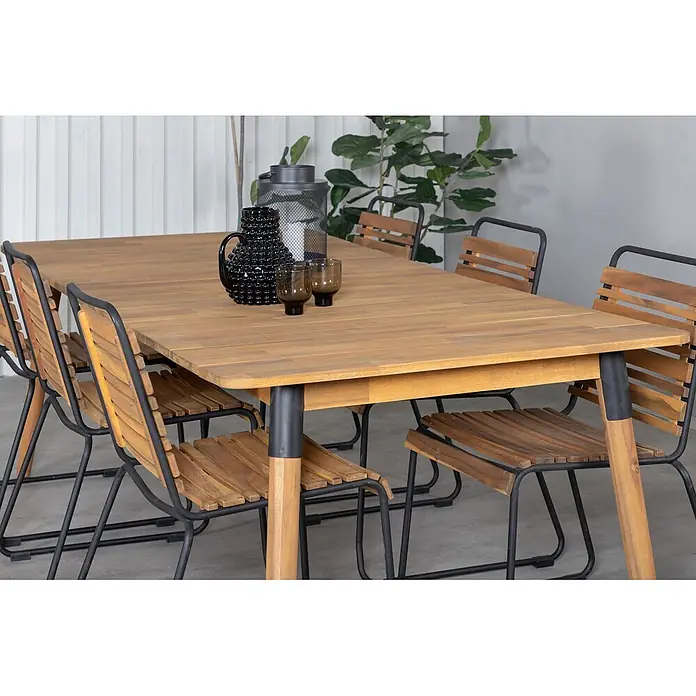 Ebuy24 Gartentisch Julian - L x B x H: 210 x 100 x 75 cm, Ø x H: 100 x 75 cm, Akazie, Stahl, Sonstige, Teak Dekor - Esstisch aus Holz mit passenden Stühlen mit schwarzen Metallgestellen, in einem Essbereich. Eine Kanne und Gläser stehen auf dem Tisch.