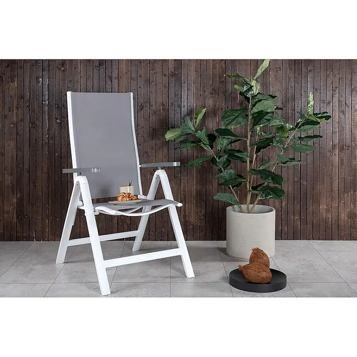 Ebuy24 Gartentisch Massa - L x B x H: 200 x 100 x 74 cm, Ø x H: 100 x 74 cm, Aluminium, Glas, Schnur, Sonstige, Weiß - Weißer und grauer Klappstuhl mit Stoffbespannung, auf dessen Sitzfläche Kaffee und ein Croissant liegen.