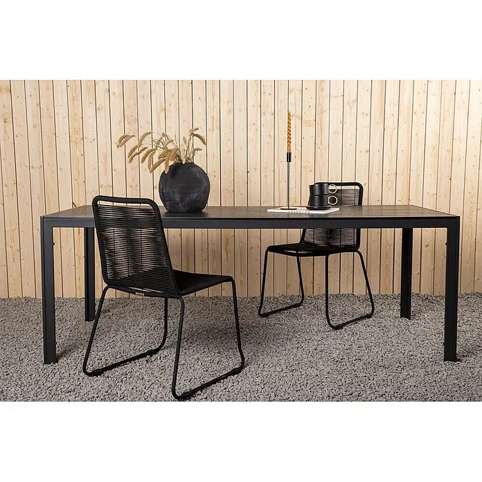 Ebuy24 Gartentisch Break - L x B x H: 205 x 90 x 74 cm, Ø x H: 90 x 74 cm, Aintwood, Aluminium, Sonstige, Schwarz - Schwarzer Outdoor-Esstisch mit zwei Stühlen mit geflochtenen Seilsitzen, auf Kies vor einer Holzwand.