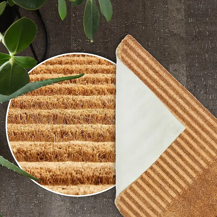 Fußmatte Coco Shape - 75 x 45 cm, Natur, Material Nutzschicht: 100 % Kokos, Streifen - Kokosfasermatte mit Borsten- und Rippenstruktur, zeigt weiße Antirutsch-Unterseite. Auf dunklem Boden mit Grünpflanzen.