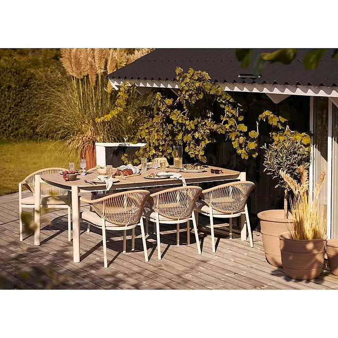 Ebuy24 Gartentisch Bella - L x B x H: 200 x 100 x 74 cm, Ø x H: 200 x 74 cm, Nonwood (PE), Aluminium, Sandfarben - Heller Outdoor-Esstisch mit geflochtenen Rattan-Stühlen und Kissen, für eine Mahlzeit auf einer Terrasse gedeckt.