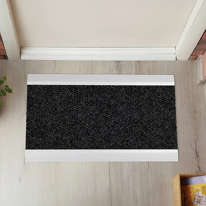 Fußmatte Aluminium - 80 x 60 cm, Anthrazit, Material Nutzschicht: 100 % Polypropylen - Schwarze Fußmatte mit silberfarbenen Rändern auf hellem Holzboden am Hauseingang.