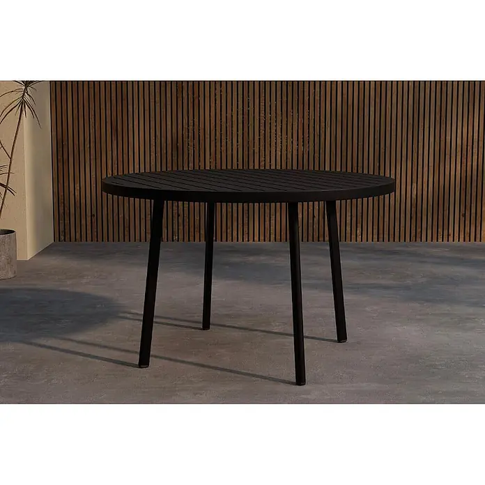 Ebuy24 Gartentisch Giardini - L x B x H: 120 x 120 x 74 cm, Ø x H: 120 x 74 cm, Aluminium, Sonstige, Schwarz - Runder schwarzer Lamellentisch für den Außenbereich auf einer Terrasse mit Holzwand.