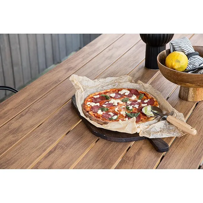 Ebuy24 Gartentisch Break - L x B x H: 150 x 90 x 74 cm, Ø x H: 90 x 74 cm, Nonwood, Aluminum, Holz - Ein Pizzaschneider mit Holzgriff und silbernem Rad liegt neben einer frisch gebackenen Pizza, bereit zum Schneiden.