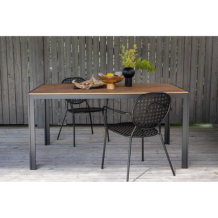 Ebuy24 Gartentisch Break - L x B x H: 150 x 90 x 74 cm, Ø x H: 90 x 74 cm, Nonwood, Aluminum, Holz - Esstisch für den Außenbereich mit Holzplatte und dunklem Metallgestell, dazu zwei schwarze Metallstühle auf einer Holzterrasse.