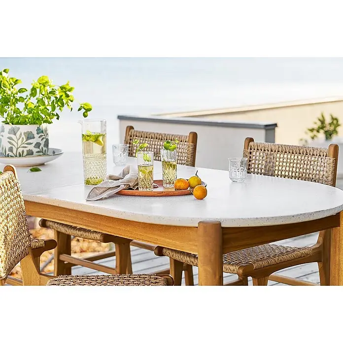 Ebuy24 Gartentisch Tirsa - L x B x H: 95 x 210 x 76 cm, Ø x H: 210 x 76 cm, Akazie, Terrazzo, Sonstige, Natur - Ovaler Outdoor-Esstisch mit gesprenkelter weißer Platte, Holzgestell und geflochtenen Rattanstühlen, für Getränke auf der Terrasse gedeckt.