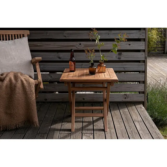 Ebuy24 Gartentisch Kenya - L x B x H: 50 x 50 x 50 cm, Ø x H: 50 x 50 cm, Teak, Sonstige, Natur - Quadratischer heller Holztisch auf einer Terrasse, mit einer Bierflasche und zwei Vasen, neben einem Stuhl.