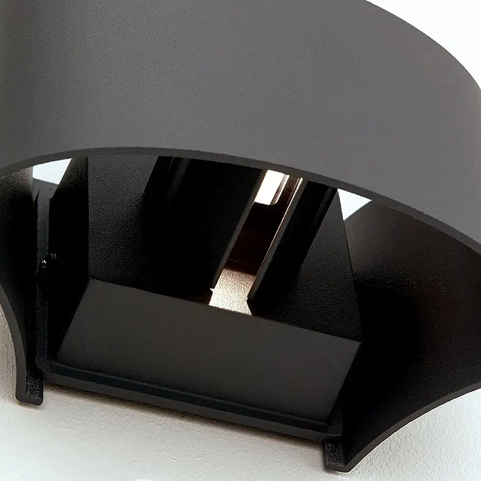 Orion Leuchten LED-Außenwandleuchte - 10 x 16,5 x 10 cm, IP54 - Nahaufnahme einer mattschwarzen gebogenen Wandleuchte mit internen Lamellen und warmer LED-Beleuchtung.