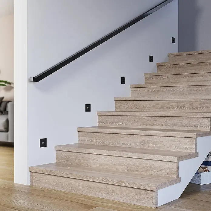 Arcchio Wandleuchte Vexi - schwarz - Moderne Holztreppe in hellem Holz mit schwarzen Wandleuchten und passendem schwarzen Handlauf.