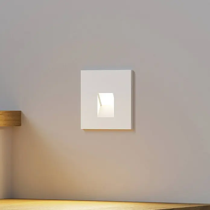 Arcchio Wandleuchte Vexi - weiß / opal - Quadratische weiße Einbau-Wandleuchte, an einer Wand installiert, die Licht nach unten auf eine Holzoberfläche wirft.
