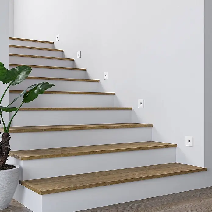 Arcchio Wandleuchte Vexi - weiß / opal - Weiße LED-Treppenleuchten beleuchten eine moderne Holz- und Weißtreppe.