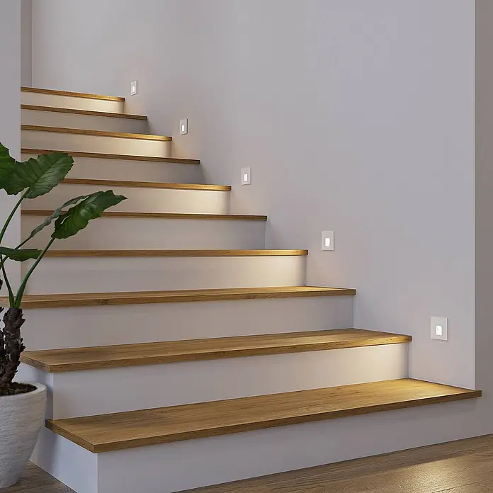 Arcchio Wandleuchte Vexi - weiß / opal - Weiße Einbau-LED-Treppenleuchten beleuchten Holzstufen in einem modernen Zuhause.