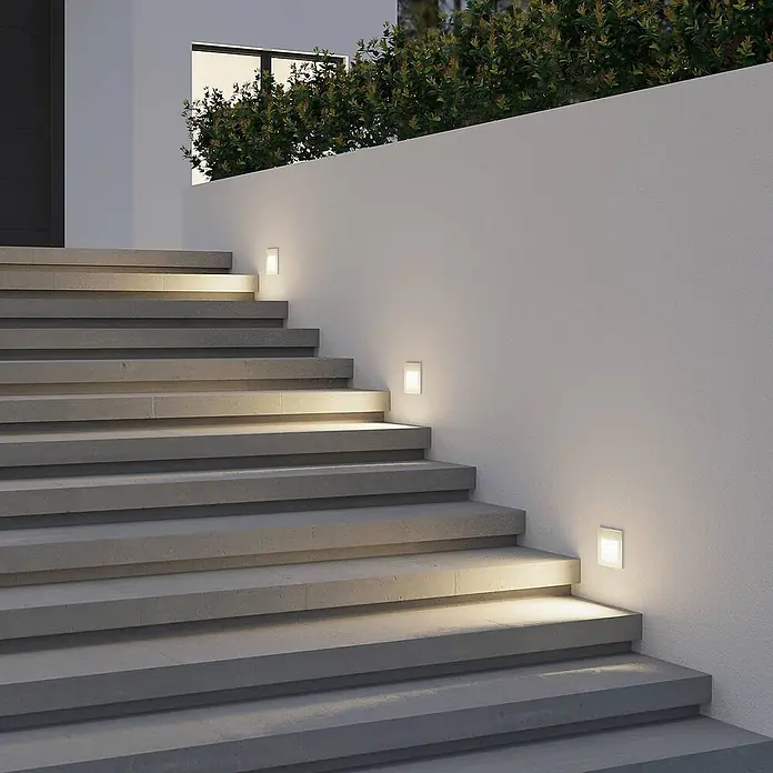Arcchio Außenwandleuchte Zamo - weiß / opal, IP65 - Quadratische, eingelassene Außenwandleuchten beleuchten eine moderne Betontreppe bei Nacht.