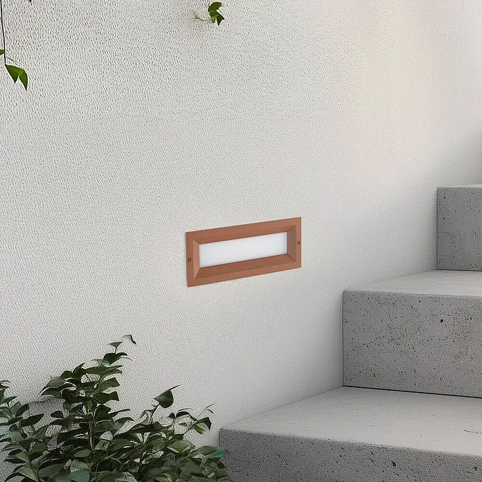 Lucande Außenwandleuchte Lachlain - braun / rost, IP65 - Rechteckige, kupferfarbene LED-Stufenleuchte an strukturierter weißer Wand neben Betontreppe.