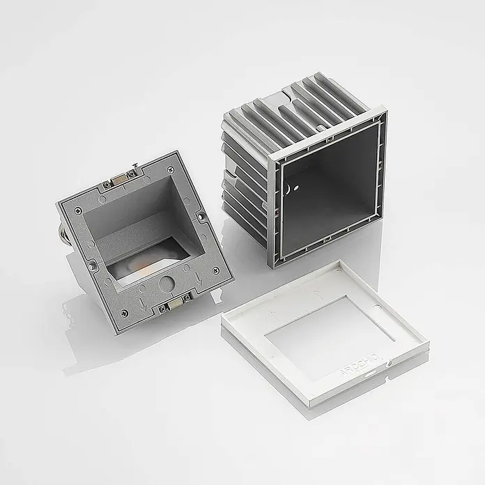 Arcchio Außenwandleuchte Zamo - weiß / opal, IP65 - Auseinandergenommener grauer Metalleinbaustrahler mit separater weißer Kunststoffblende.