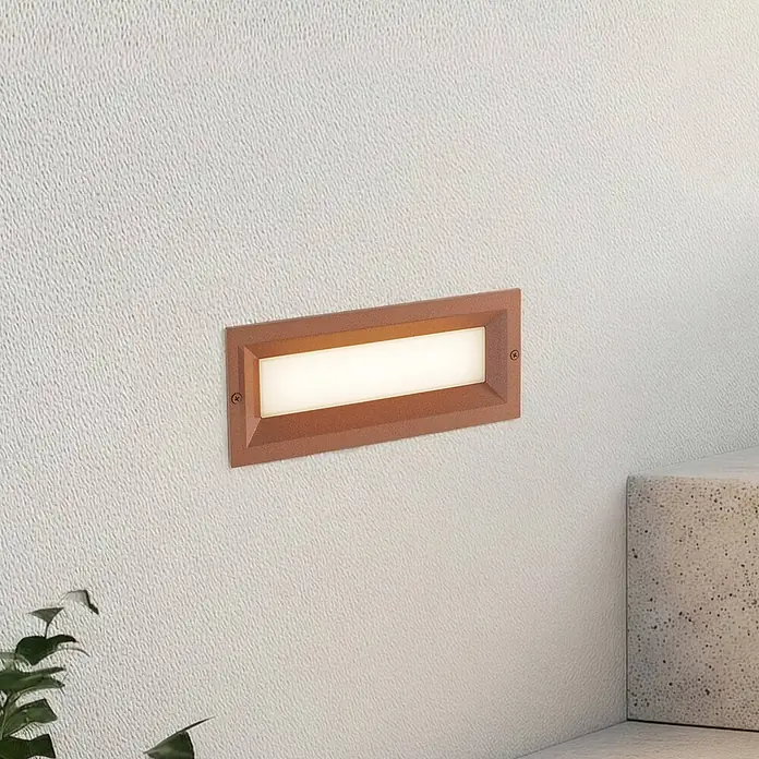 Lucande Außenwandleuchte Lachlain - braun / rost, IP65 - Rechteckige braun/kupferfarbene Außenwandleuchte an einer strukturierten Wand, strahlt warmweißes Licht aus.