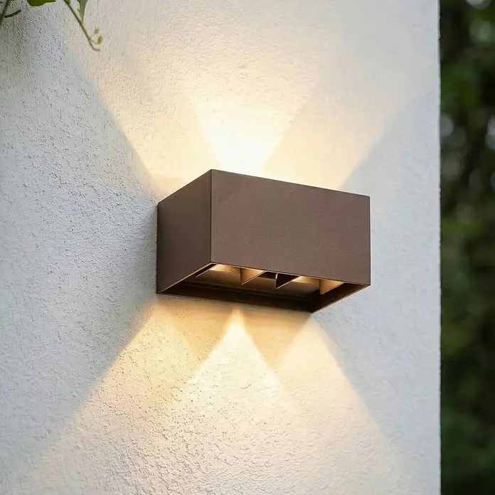 Lindby Außenwandleuchte Nivar - 10 x 20 x 10 cm, braun / rost, braun / rost, IP54 - Moderne, dunkelbraune, rechteckige Außenwandleuchte wirft warmes Licht nach oben und unten an eine strukturierte Wand.