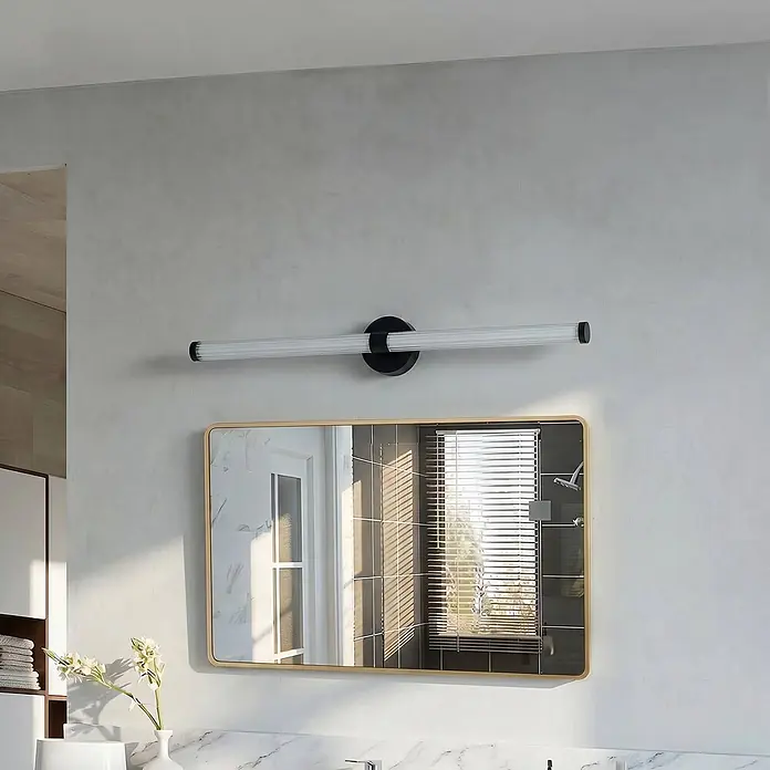 Lucande Wandleuchte Melisa - schwarz, weiß / opal - Moderne schwarze und weiße gerillte Röhren-Waschtischleuchte über einem goldgerahmten Spiegel im Badezimmer.